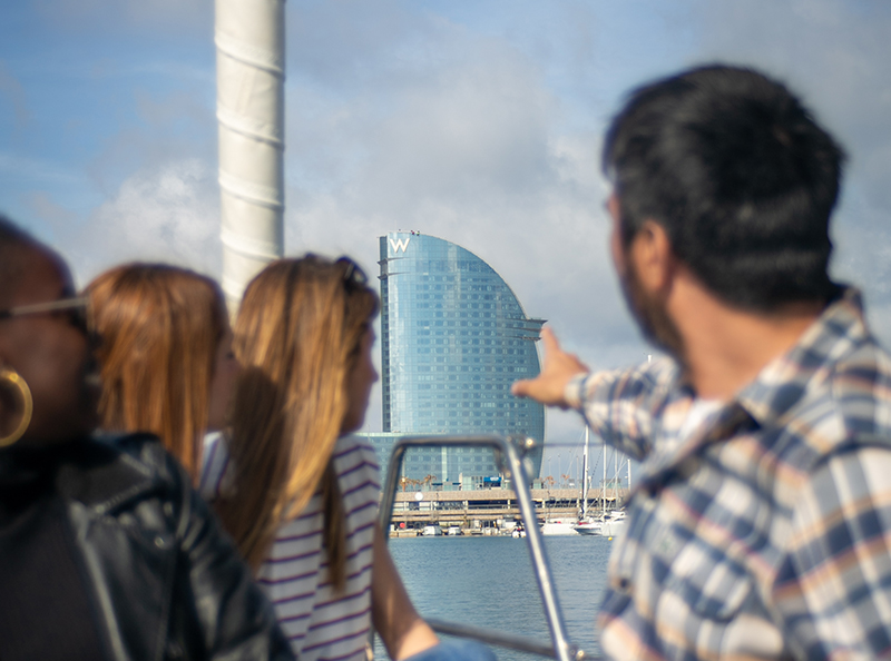 A group of people on a boat tour. They're looking the city of Barcelona